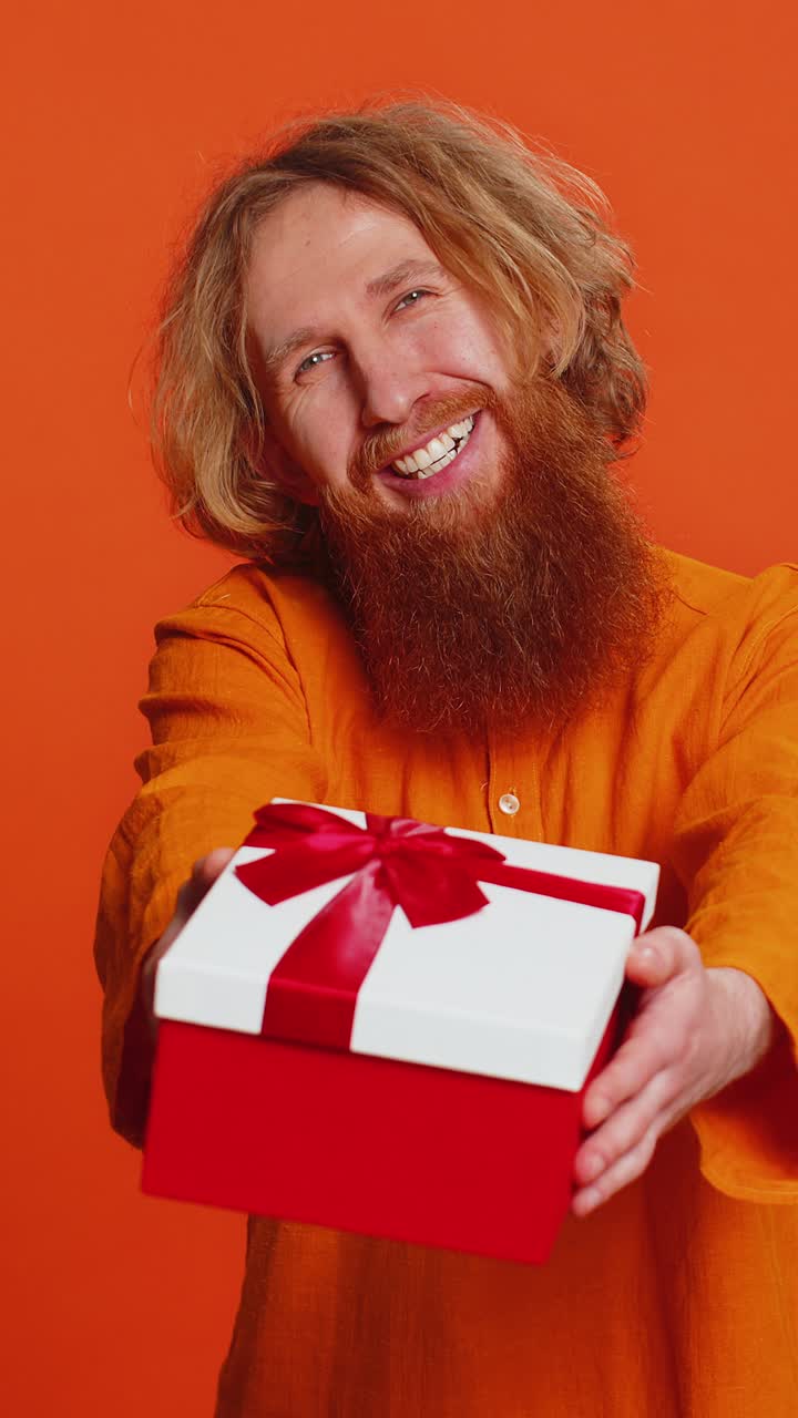 Smiling young man presenting birthday gift present box stretches out hands promotion discount sale