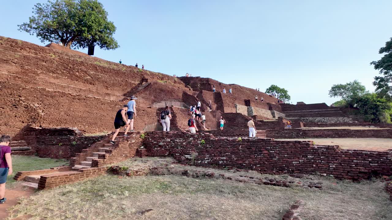 Tourists climbing ancient ruins at sigiriya lion rock, a unesco world heritage site in sri lanka, on a sunny day