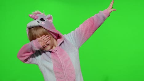 little blonde child girl dancing, celebrating, performing dab dance in unicorn pajamas costume