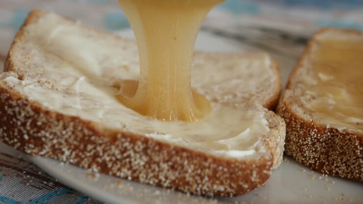 Breakfast with buttered bread slice and yellow honey spread with a silver knife