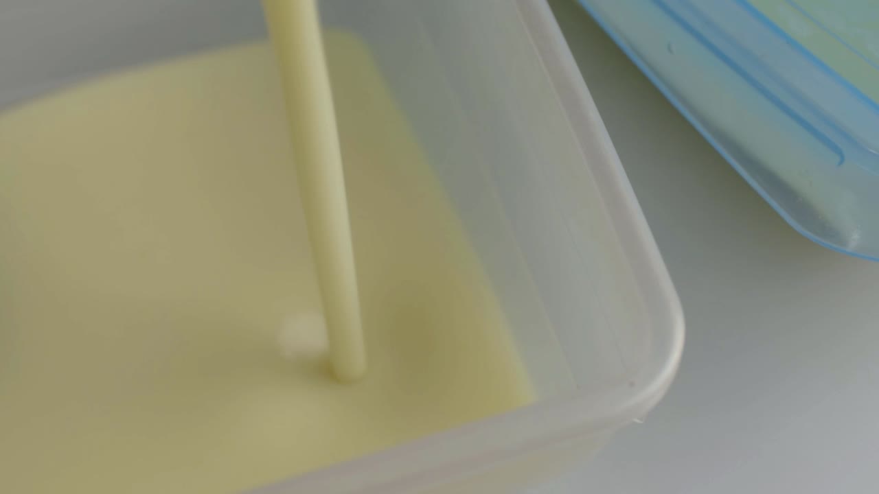 Pouring creamy soup into a plastic storage container