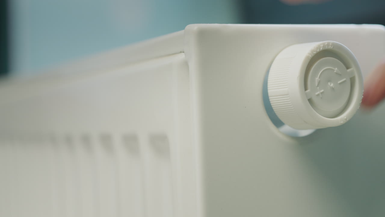 A man's hand regulates the temperature on a heating radiator. Energy Saving