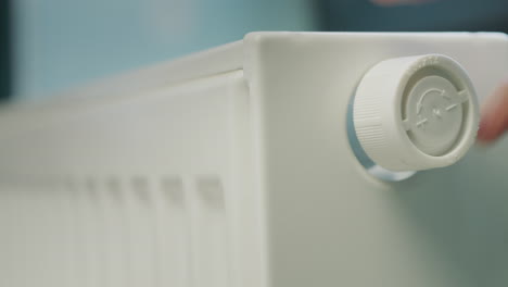 A-man's-hand-regulates-the-temperature-on-a-heating-radiator.-Energy-Saving