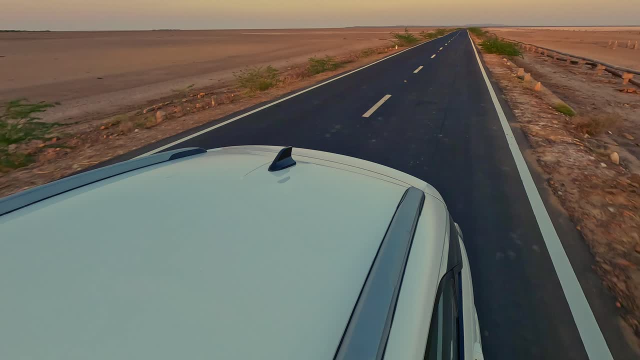 Driving forward on the road to heaven in Kutch, Gujarat India an ethereal journey through glowing salt flats, with the endless white Rann stretching endlessly on both sides under the vast sky 4K