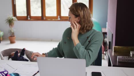 Video-Einer-Kaukasischen-Mutter,-Die-Von-Zu-Hause-Aus-Mit-Ihrem-Neugeborenen-Am-Laptop-Arbeitet