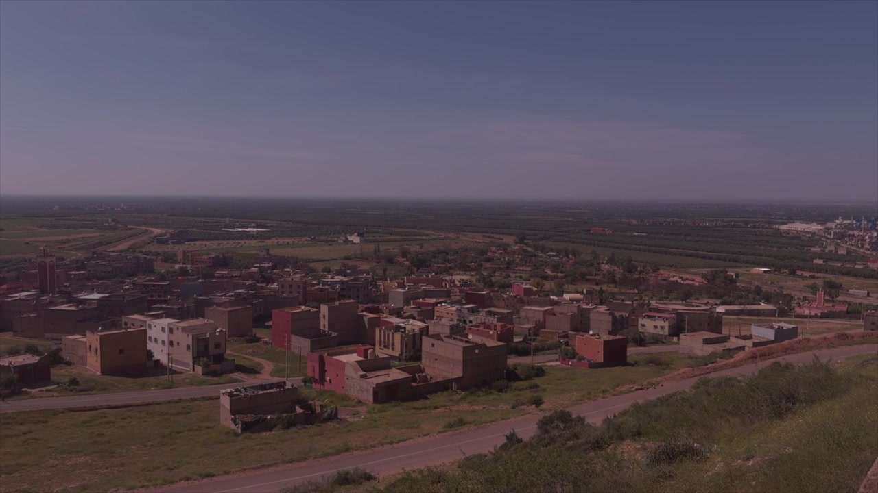 Tranquilas casas marroquíes dispersas por vastas llanuras rurales bajo una luz pálida y brumosa.