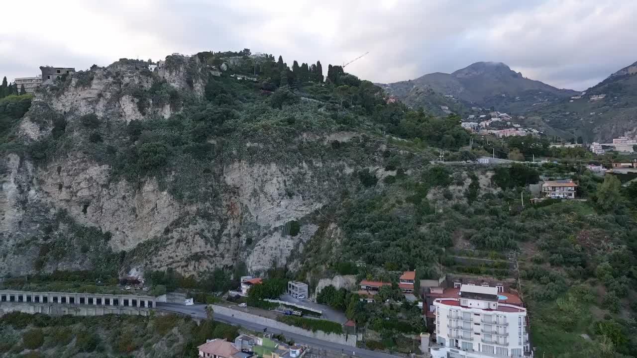 Luftfoto af en smuk kystby på en bjergrig bjergside på Sicilien
