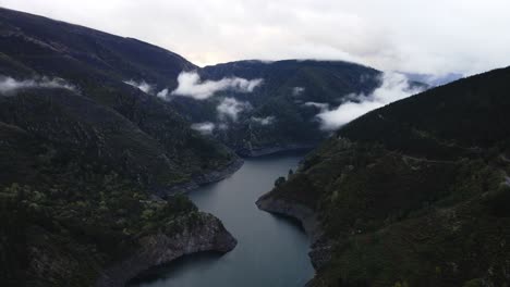 Bosque-Desierto-Montaña-Rodeado-Lago-Parcialmente-Nublado-Vista-Aérea