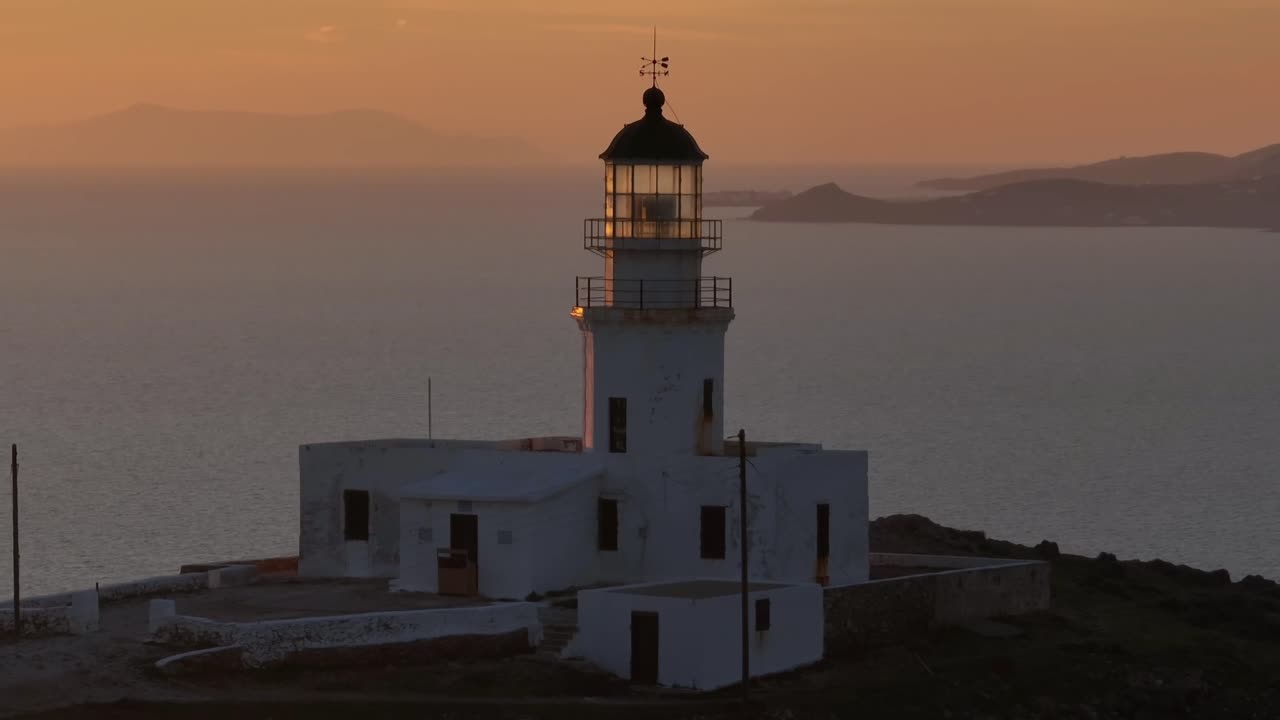 Orbiting a lighthouse at sunset, with the golden sun and the Aegean Sea creating a breathtaking backdrop