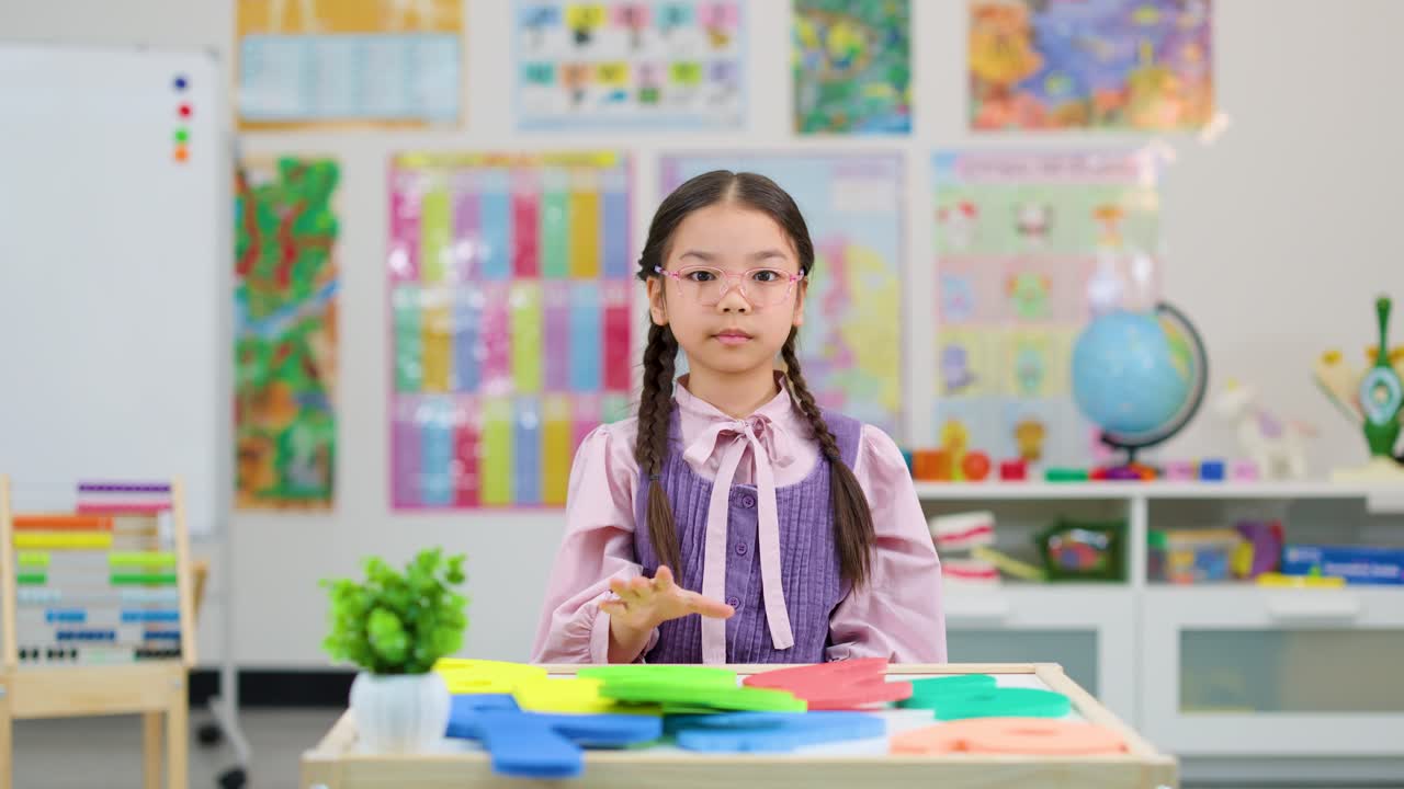 A girl holding the number 6 in a classroom