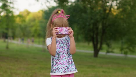 cute little girl in a unicorn costume smiling in a park