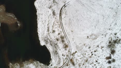 camino en la tierra cubierta de nieve a lo largo del río durante el invierno 4k