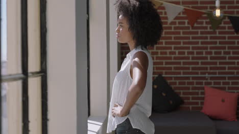 beautiful african american woman looking out window planning ahead relaxing at home pensive black female in sunny new york apartment