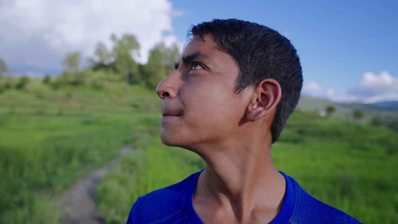 Pensive Indian child in paddy field scanning surroundings with worried eyes, emotional village portrait, 4k video