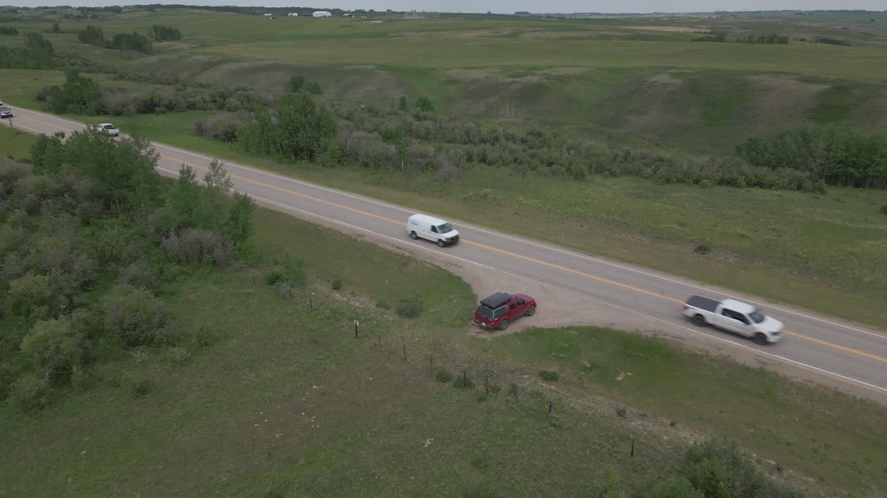 Vista aérea de una carretera en la pradera con un vehículo detenido en el arcén