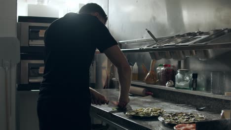 fabricante de pizza cortando perejil en la cocina