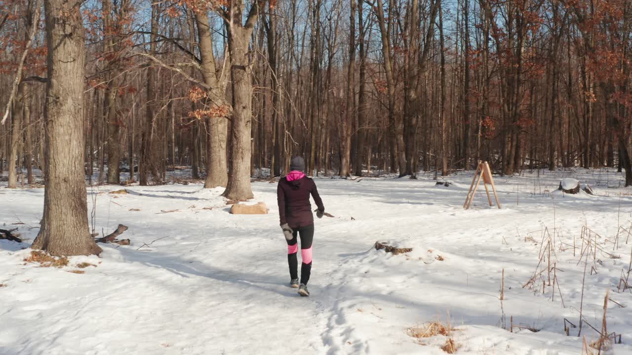 Mulher com Roupa de Exercício Ativa Caminhando Sozinha em Trilha Florestal Coberta de Neve
