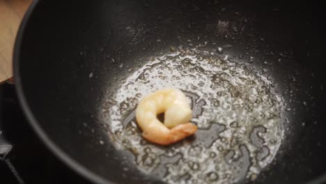 unrecognizable person output fried prawn from pan into bowl