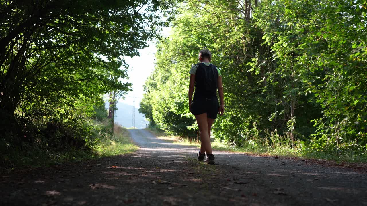 Mulher caminhando em uma trilha na floresta com uma mochila