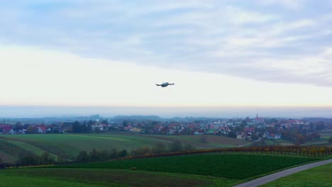 drone filming another drone flying over countryside farmland on a cloudy day