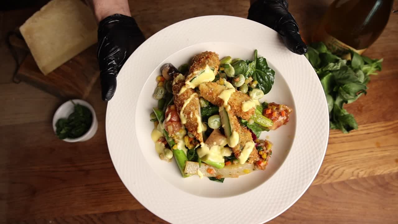 Chef's Gloved Hands Presenting a Gourmet Fried Chicken and Vegetable Dish