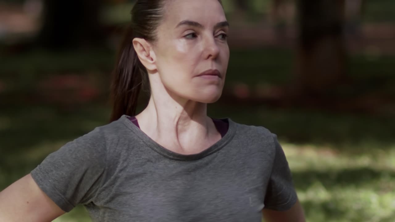 Mujer estirando la parte superior del cuerpo, entrenamiento en el bosque, plano medio, cámara lenta