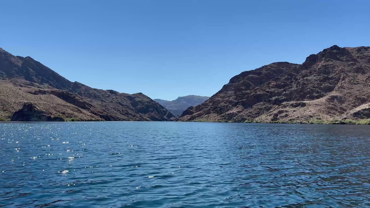 las hermosas aguas azules del río colorado contra las montañas de roca roja de las montañas eldorado en nevada.
