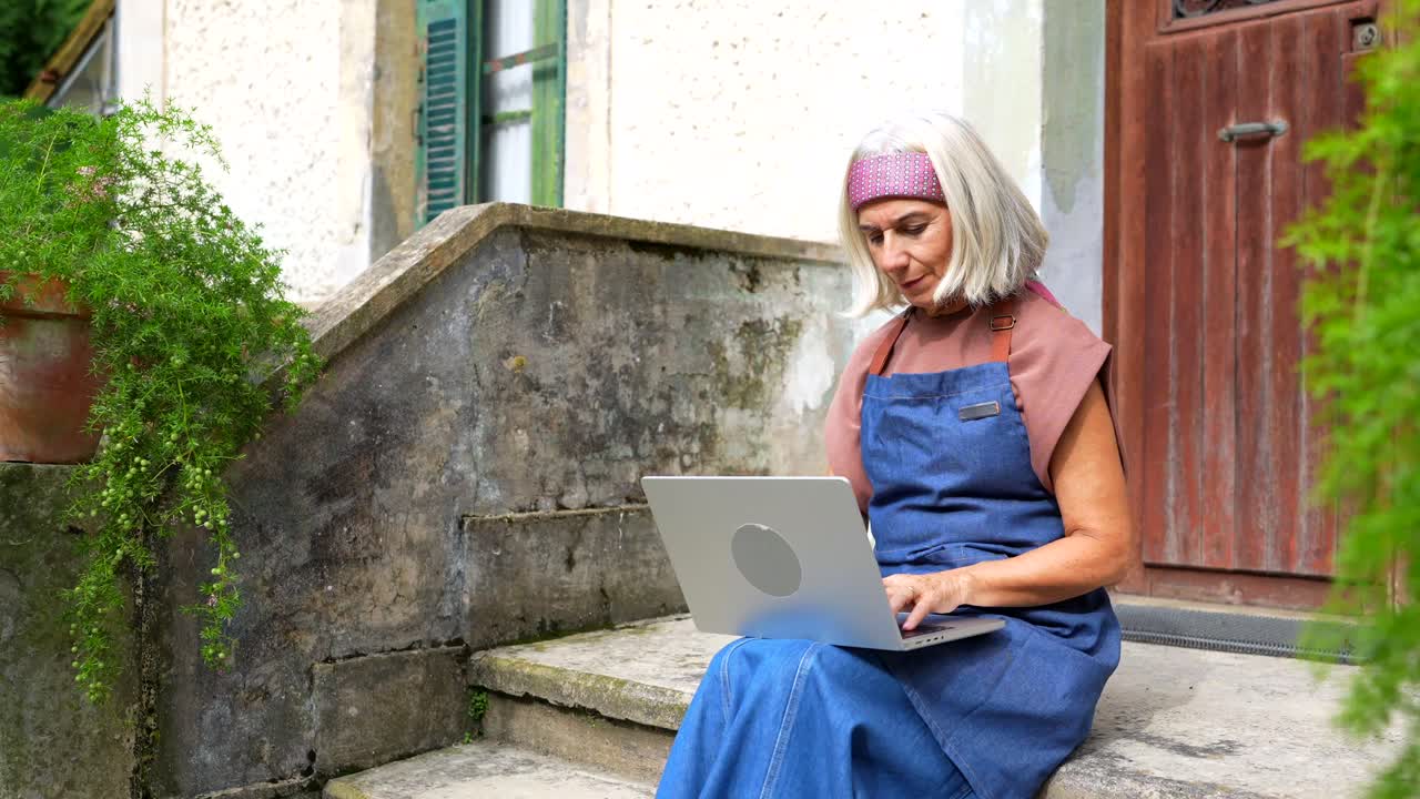Senior woman using laptop on stairs