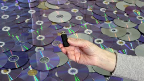 woman holding usb memory stick on cd and dvd discs background