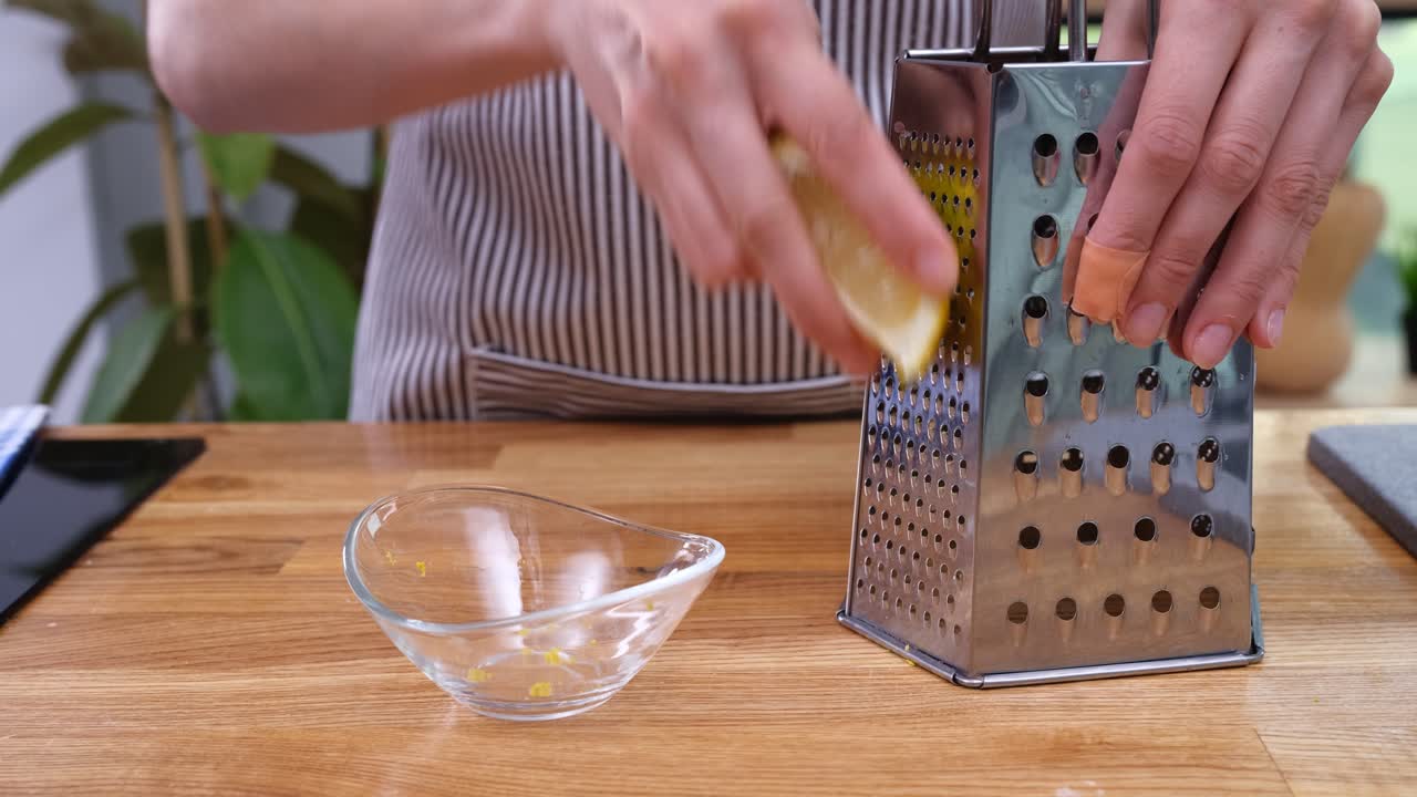 Primo piano di mani che grattugiano scorza di limone fresca in una ciotola