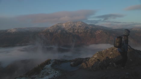 Static shot of a hiker admiring the view of a snow-covered Ben Venue and leaving
