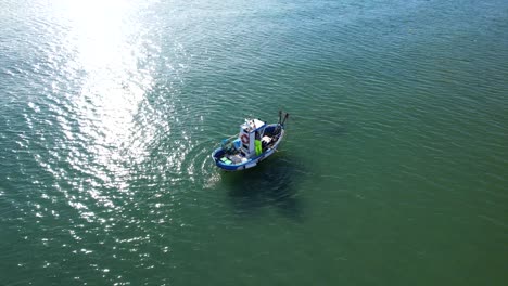 Boat-gently-rocks-in-ocean-as-it-tows-long-nets-dragging-along-sandy-floor