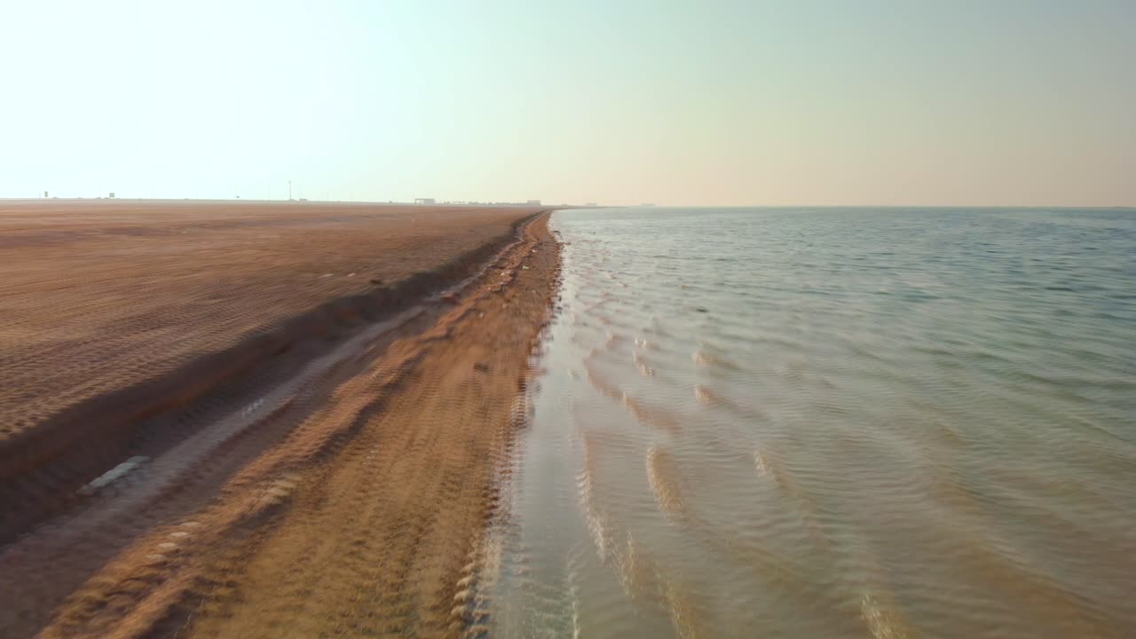 drone acelerando a baja velocidad a lo largo de la desolada costa del desierto, abu dhabi, emiratos árabes unidos