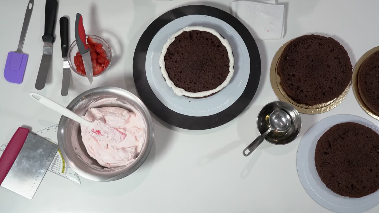 크림으로 인 케이크의 을 조심스럽게 만지기 위해 아이싱 스파라를 사용하는 베이커의 앞.