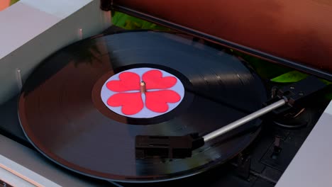 disco de vinilo negro con corazones rojos girando en el tocadiscos de dj. reproductor de discos anticuario. aguja tocando álbum de discos equipo de música popular para los años 60, 70, 80, 90, concepto de amor de cerca, macro