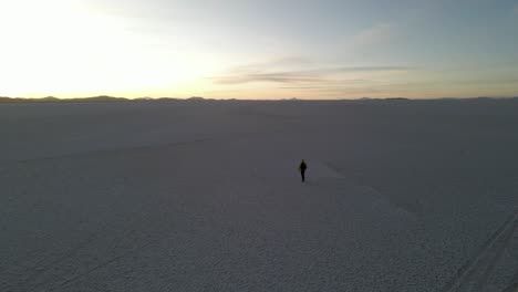 drone captures people walking across vast white salt flat in uyuni during peaceful daylight