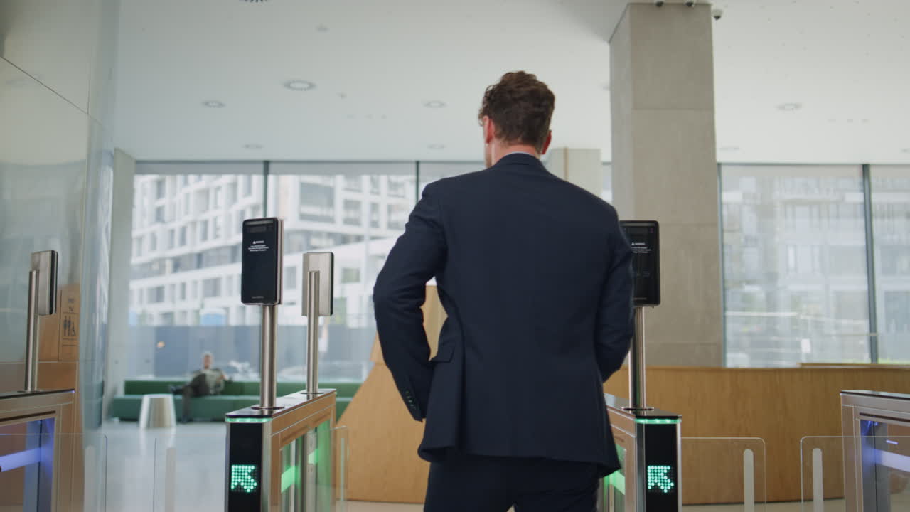 우아 한 사업가 가 사무실 건물 을 떠나 스마트워치 를 사용 하여 회전문 을 열고 있다