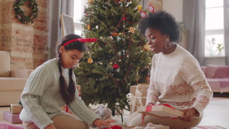 african american mother and daughter packing christmas gifts at home