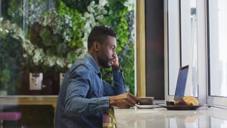 african american businessman using laptop drinking coffee in cafe