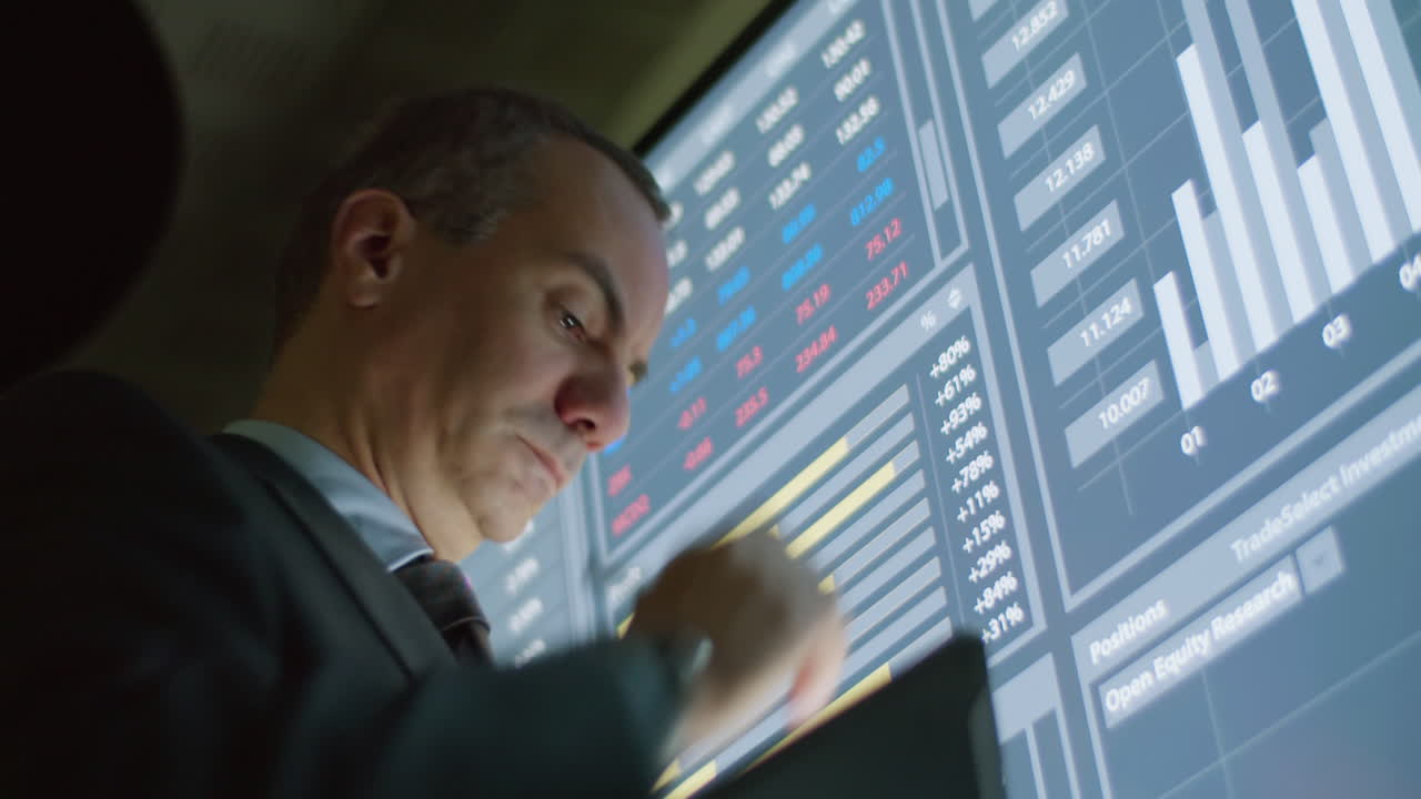 hombre serio escribiendo datos en tableta desde pantalla digital