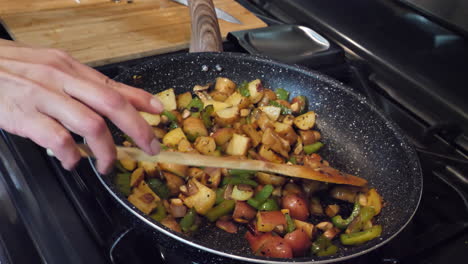 cooking mixed vegetables and fried potatoes in frying pan at home, slow motion