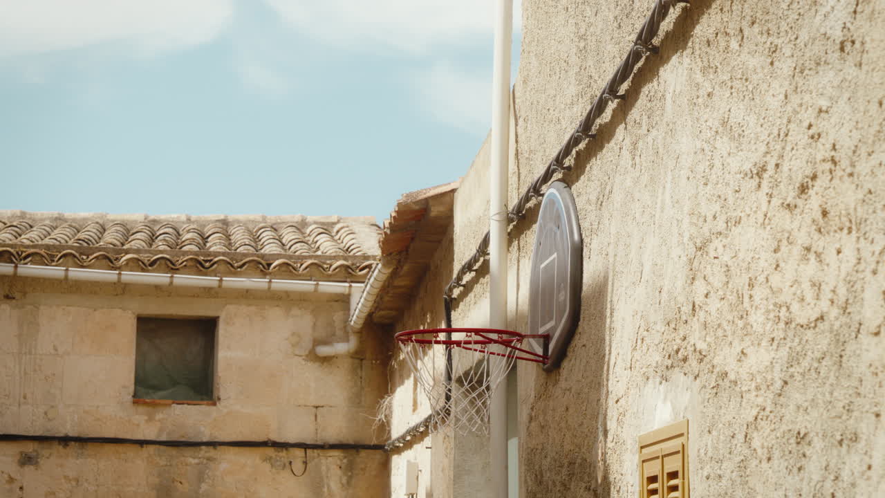 Rustic basketball hoop in Spanish courtyard, embodies passion and energy. Perfect for travel and sports projects celebrating European culture.