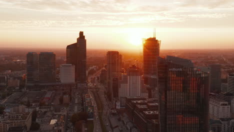 Slide-and-pan-footage-of-group-of-tall-modern-buildings-in-city-centre.-Evening-scene-against-setting-sun.-Warsaw,-Poland