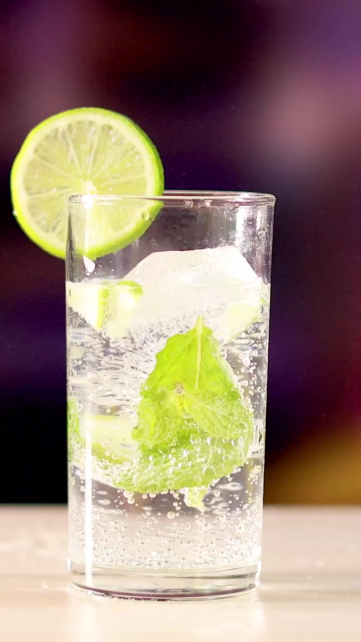 Una ripresa verticale di un cocktail mojito frizzante con guarnizione di lime e foglie di menta