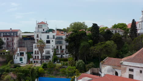 Drone-camera-following-terrain-profile-and-rising-over-hill.-Flying-above-houses-to-old-Saint-George-Castle.-Revealing-city-panorama.-Lisbon,-capital-of-Portugal.