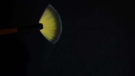 slow motion of a make up brush with blue powder explosion and burst on black background