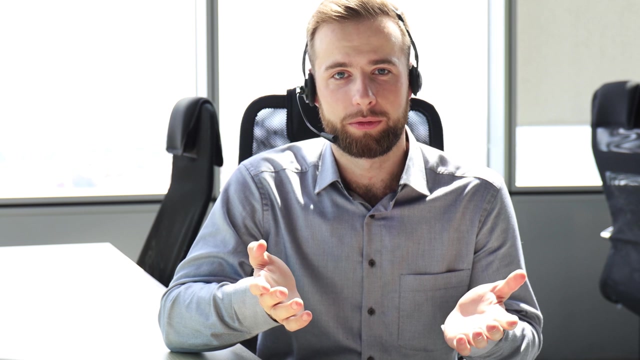 Giovane uomo con le cuffie che parla durante una videochiamata in ufficio