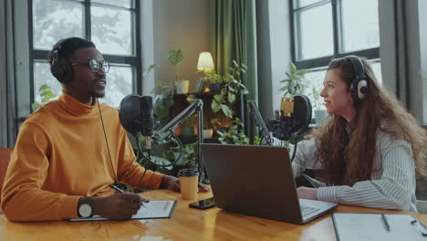 black podcast host interviewing young female guest in recording studio