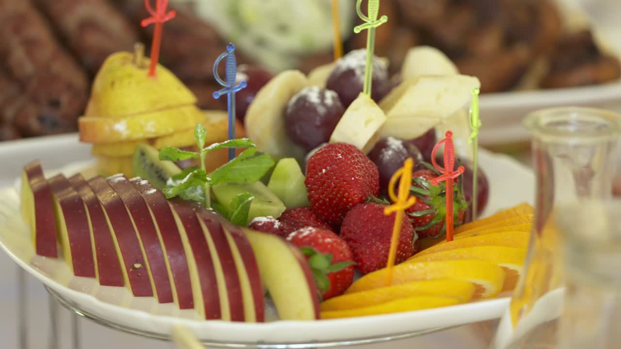 plato de frutas frescas en la mesa de la cena festiva. horquillas de frutas en rodajas variadas