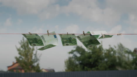 several banknotes of one hundred euros are drying on a clothesline. money laundering concept